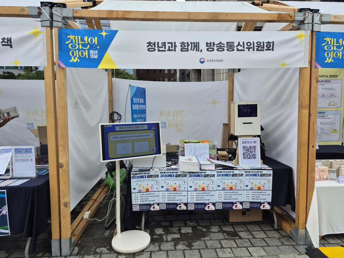 행사 부스에 퀴즈 화면과 참여형 키오스크가 설치된 모습